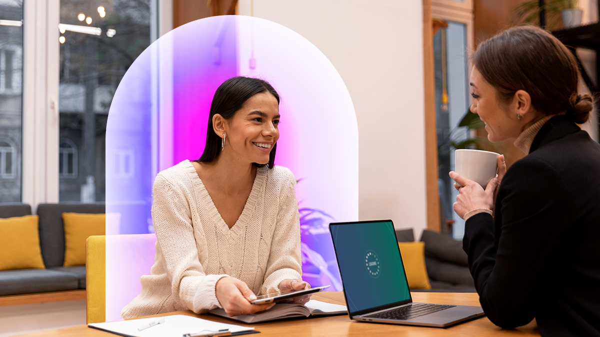Corporate women sitting at a desk with a laptop having a conversation